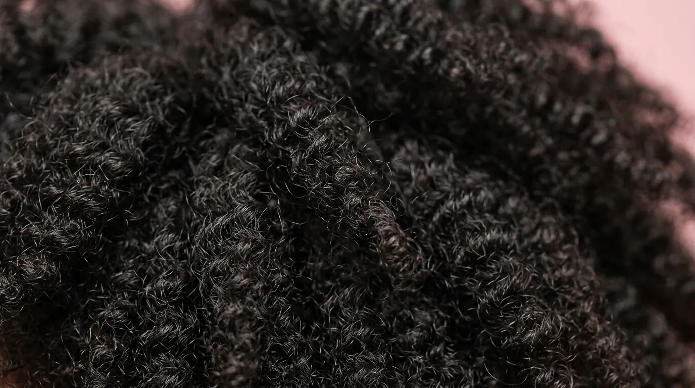 Gros plan sur une texture de cheveux crépus noirs, denses et volumineux